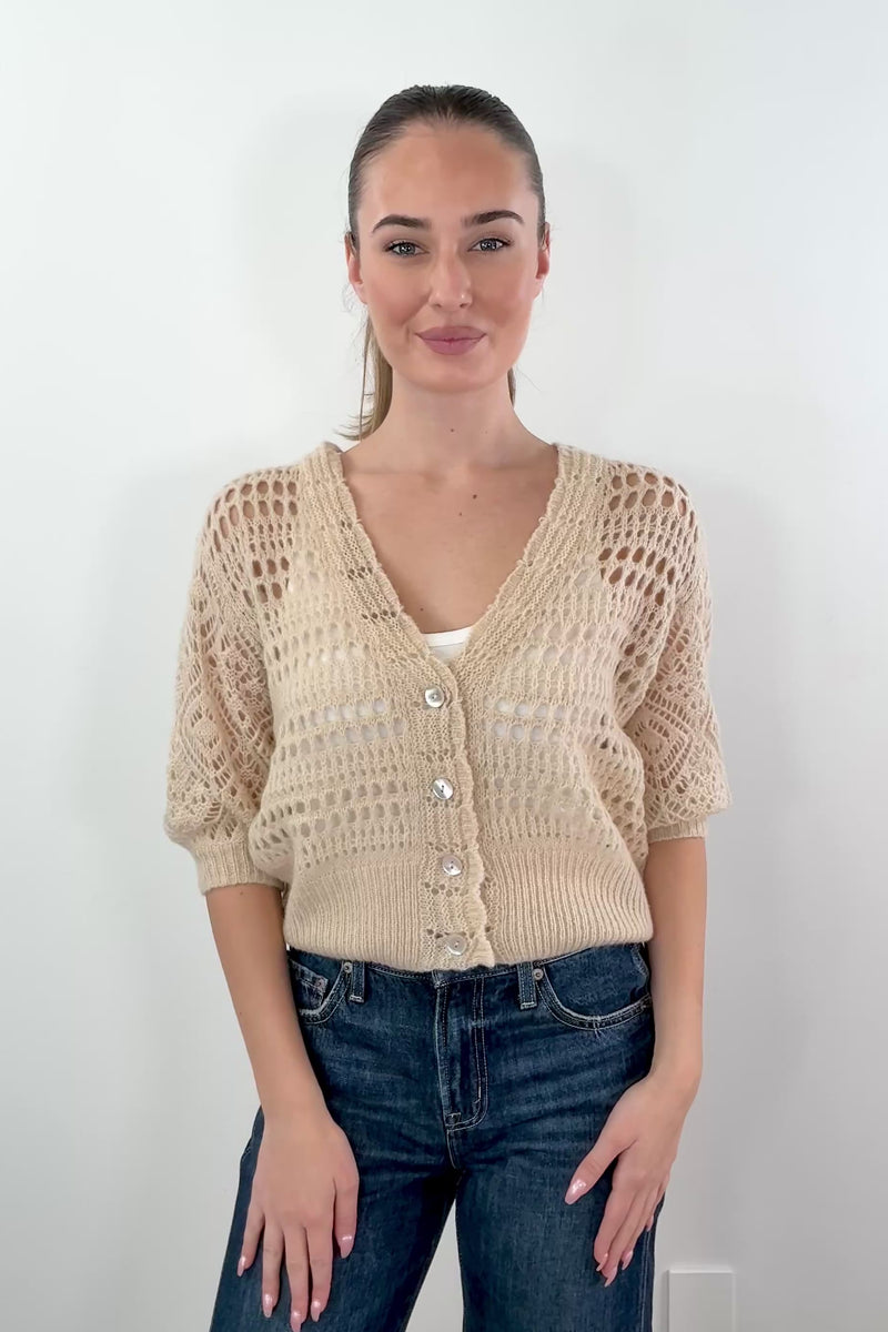 video of a woman wearing a pointelle knit cardigan in latte with pearl white buttons