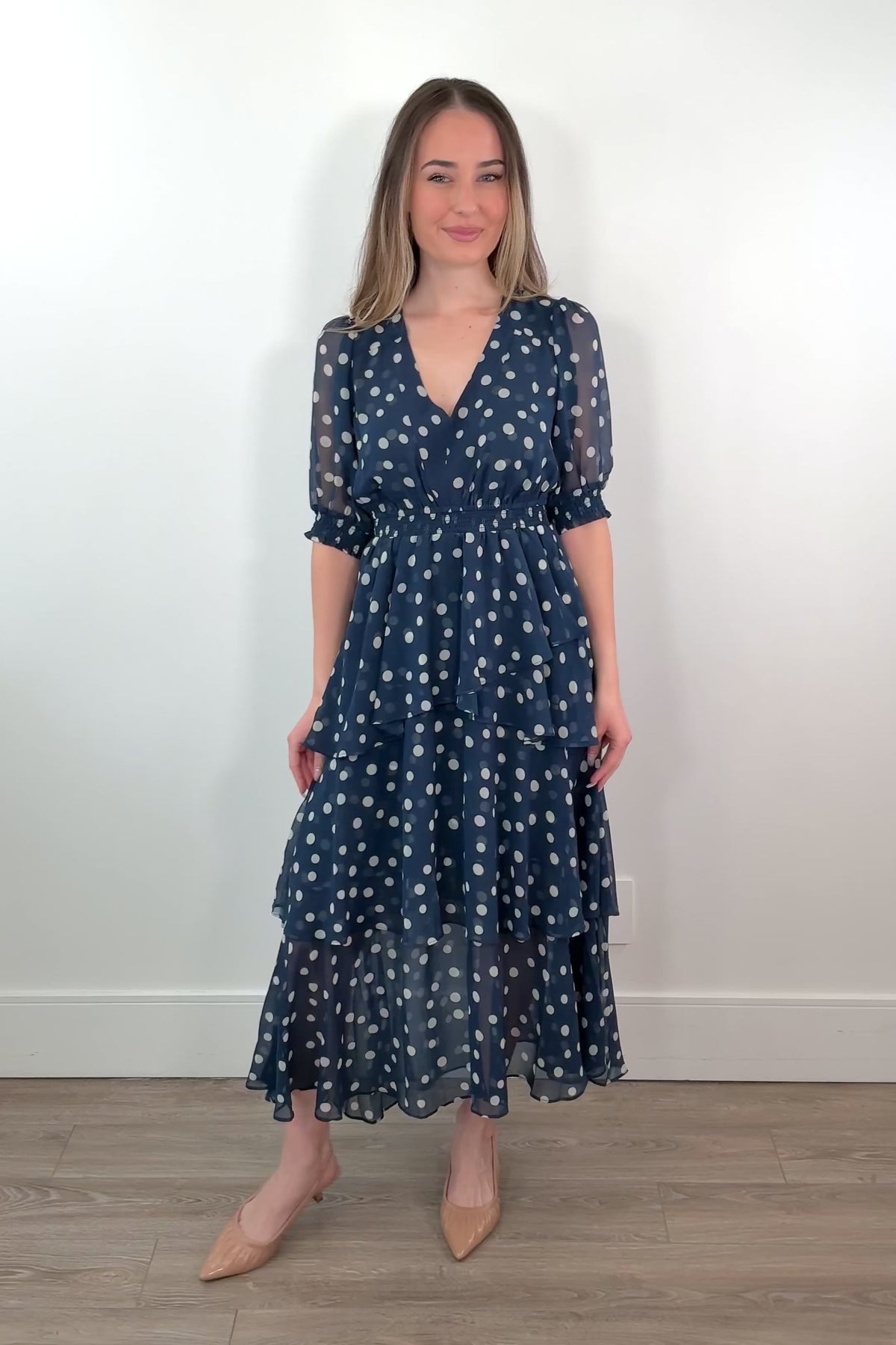 video of a woman wearing a navy midi ruffle dress with white polka dots