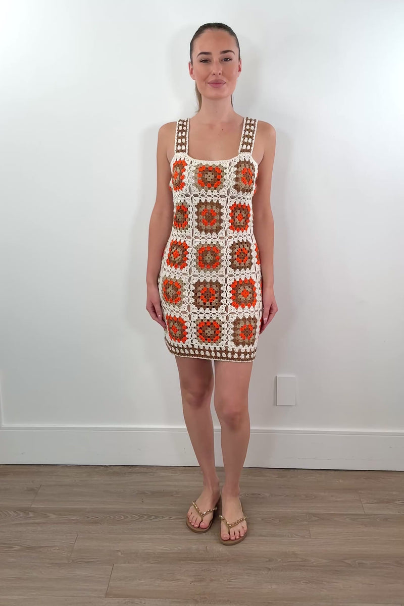 video of woman wearing an orange, white and beige patterned crochet short dress 