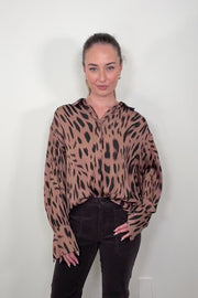 Video of woman wearing a brown printed blouse 