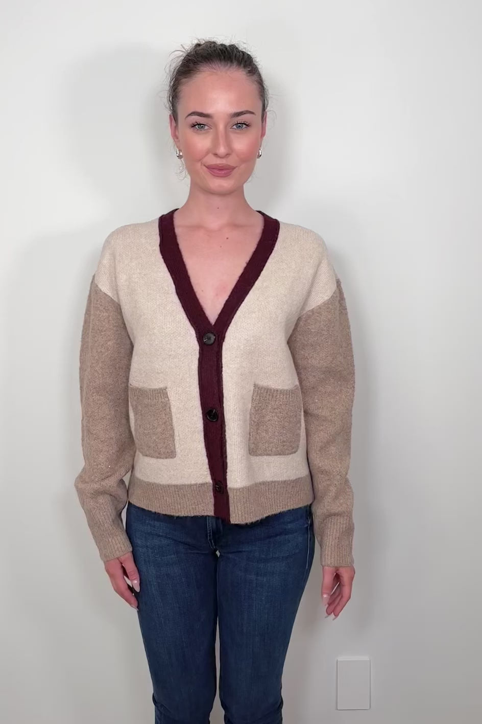 Video of woman wearing a colour block beige and burgundy cardigan with pockets