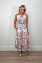 Video of a woman wearing white sleeveless midi dress with a blue, red and orange pattern as well as crochet detailing turning around to show the back