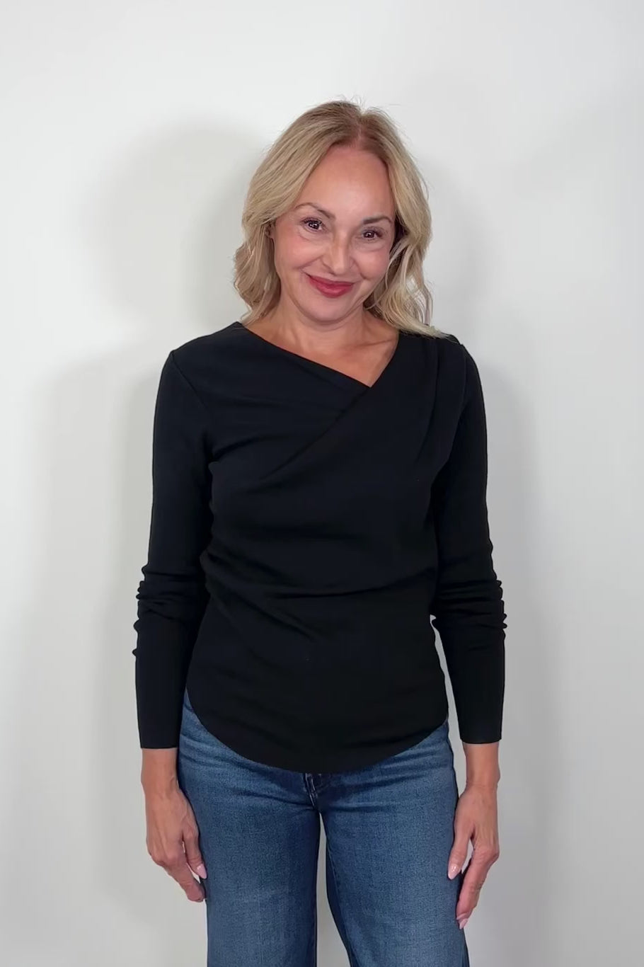 Video of a woman wearing black drape neck knit top