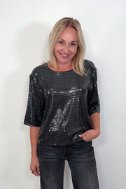 Video of woman wearing a half sleeve shimmery crew top turning around to show the back