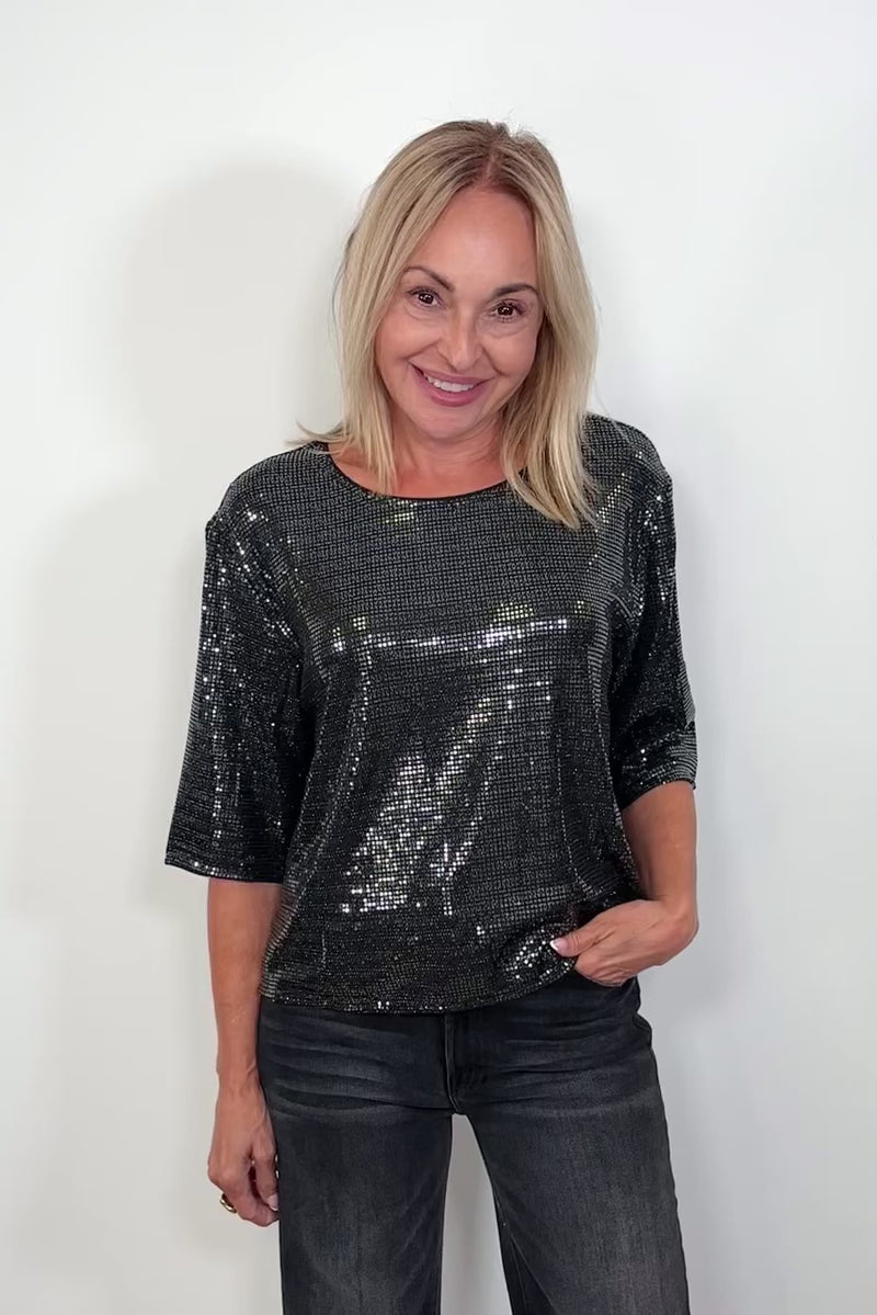 Video of woman wearing a half sleeve shimmery crew top turning around to show the back