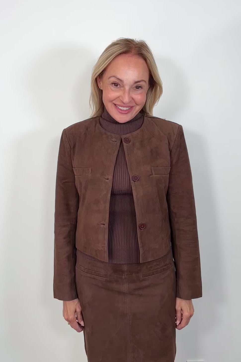 Video of woman wearing a collarless brown suede jacket 