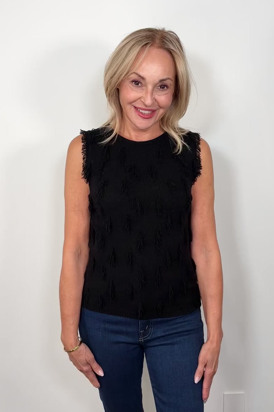 Video of a woman wearing a black tank top with fine gauge fringes 