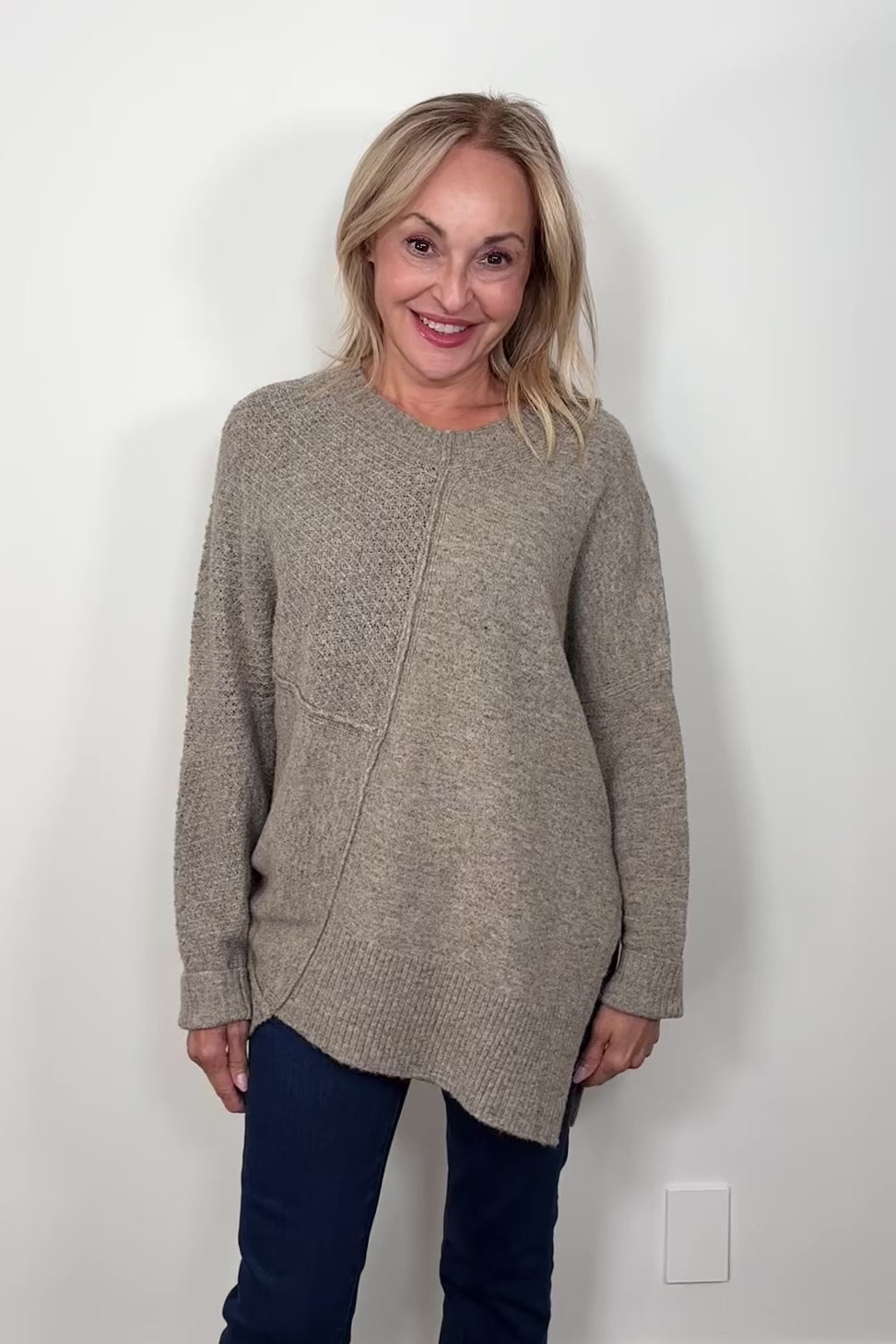 Video of woman wearing a greige asymmetrical sweater 
