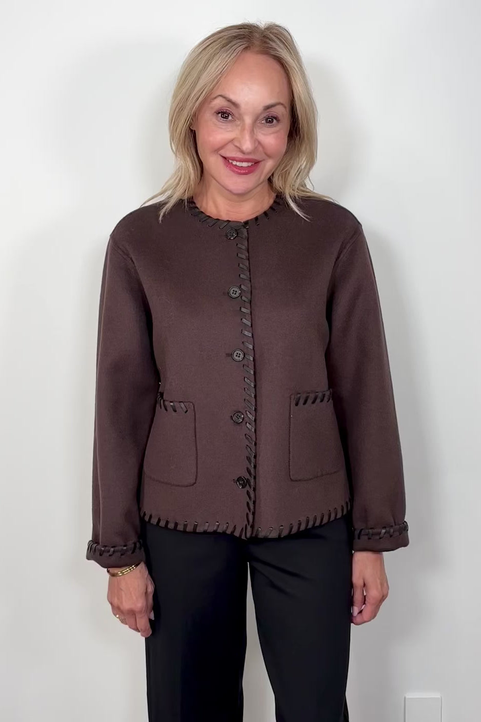 Video of woman wearing a brown wool coat with whipstitch detailing