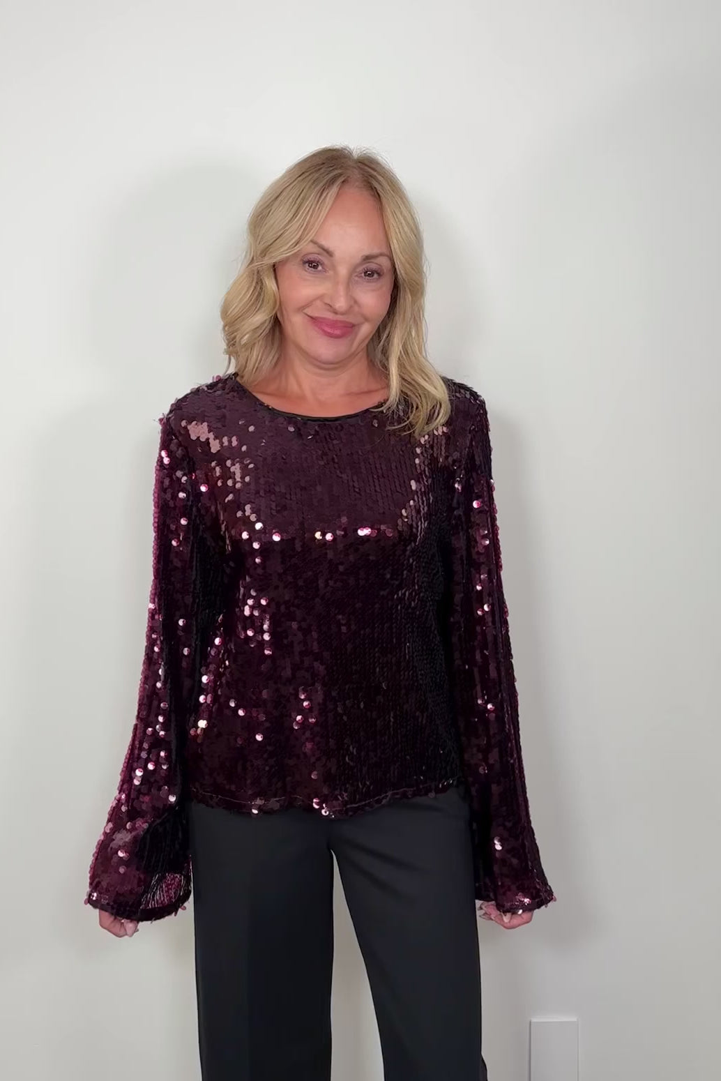 video of a woman wearing a maroon sequin long flared sleeves top