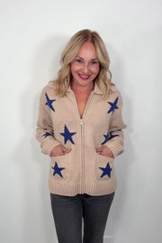 Video of a woman wearing a beige zip-up sweater with blue star patterns and front pockets