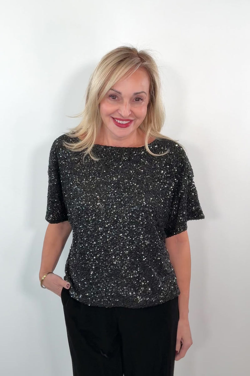 video of a woman wearing an oversized black sequin top 