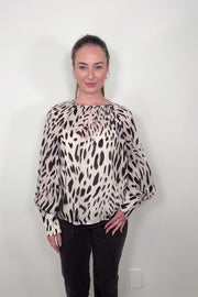 Video of woman wearing a sheer printed blouse with a cami underneath
