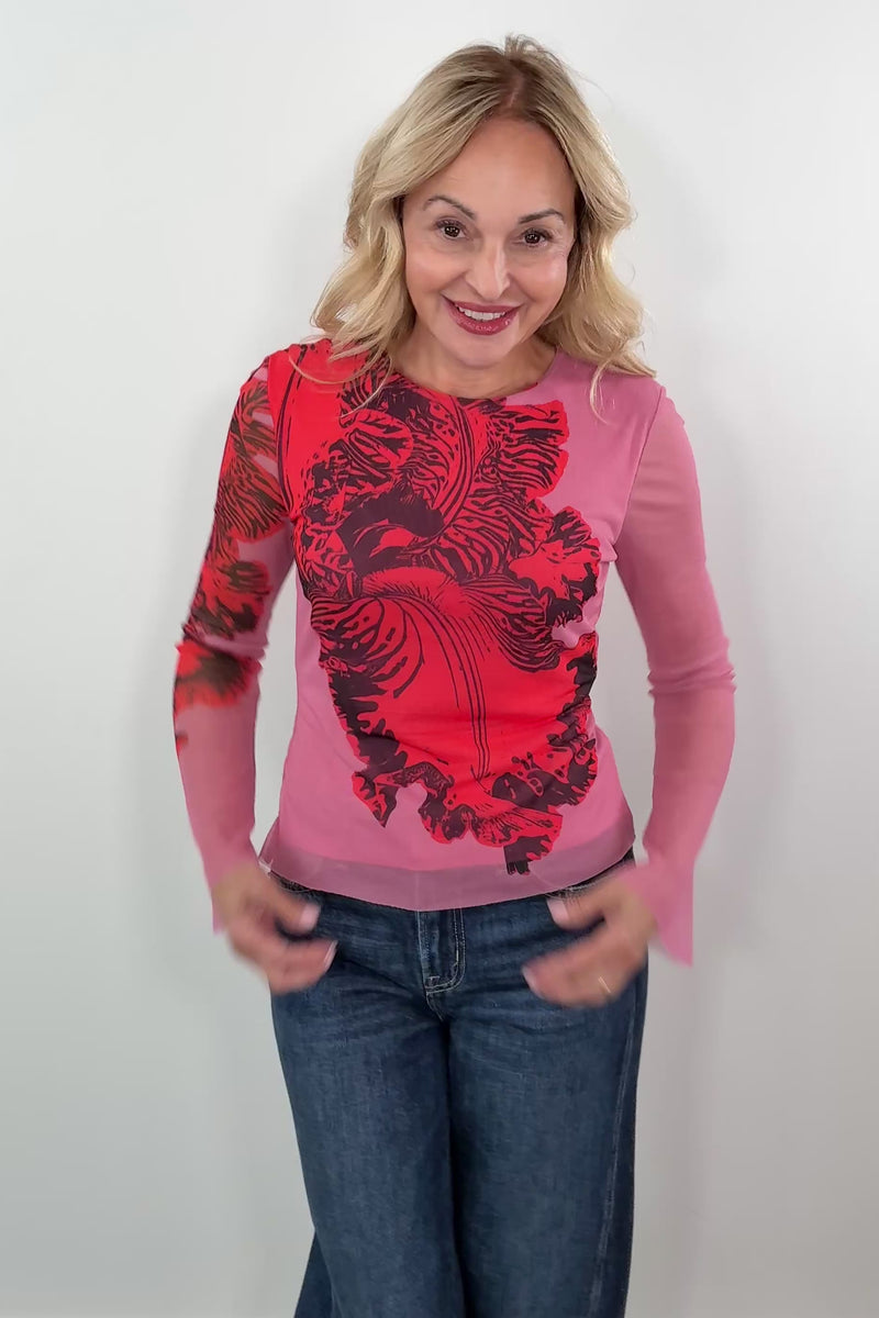 Video of a woman wearing a pink bell sleeve mesh lined top with a red orchid print