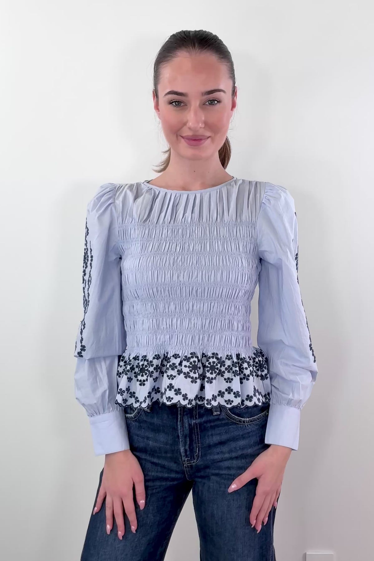 video of woman wearing a light blue smocked blouse with black detailing