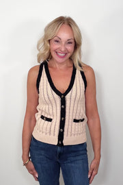 video of a woman wearing a beige knitted vest with black trim on a white background