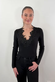 video of  a woman wearing a black ribbed top with lace details along the neckline