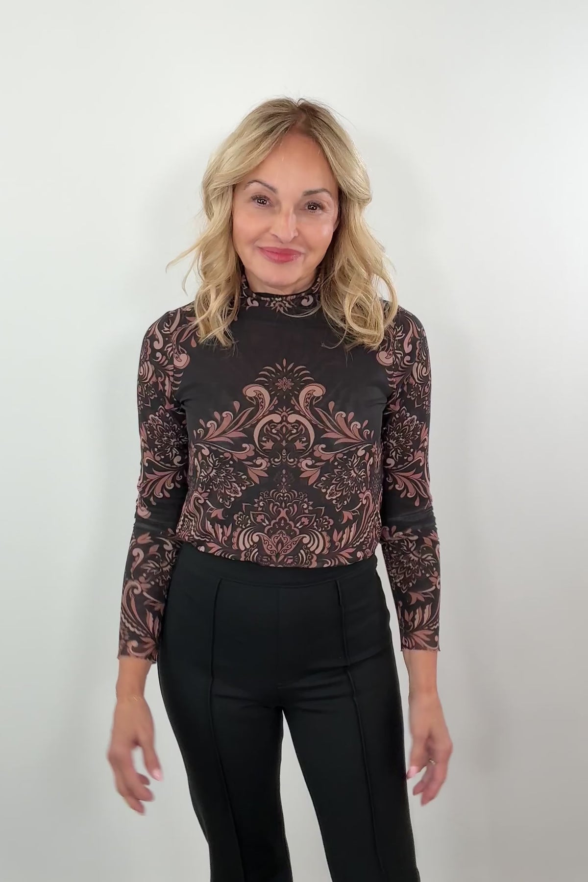 video of a woman wearing a patterned mesh long sleeve turtle neck