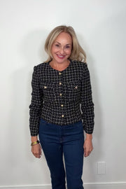Video of a woman wearing a navy houndstood patterned blazer with gold hardware