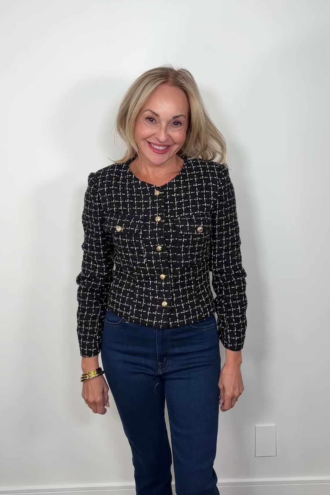 Video of a woman wearing a navy houndstood patterned blazer with gold hardware