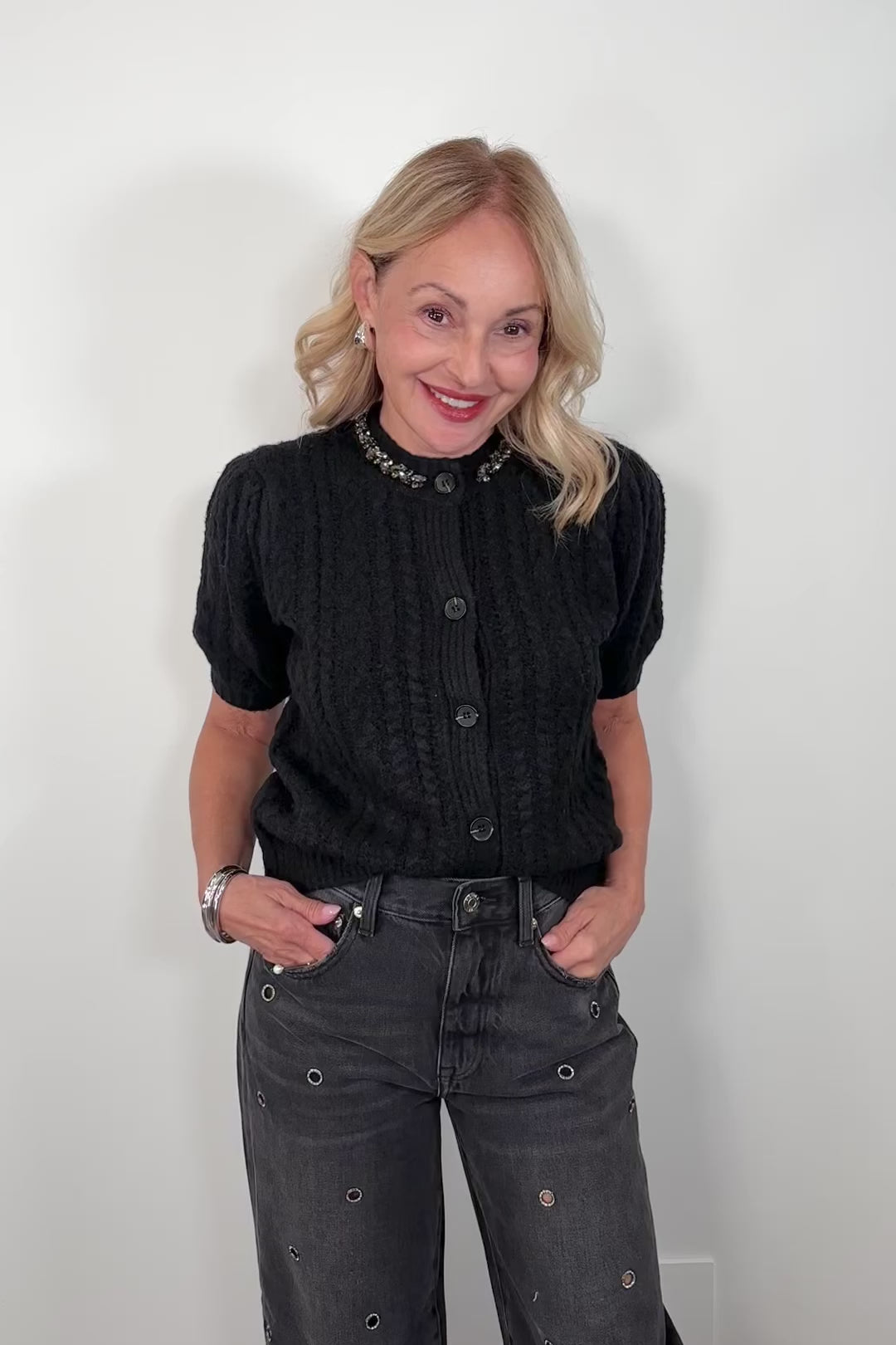 Video woman wearing a black knit button up cardigan with embellishments in the collar