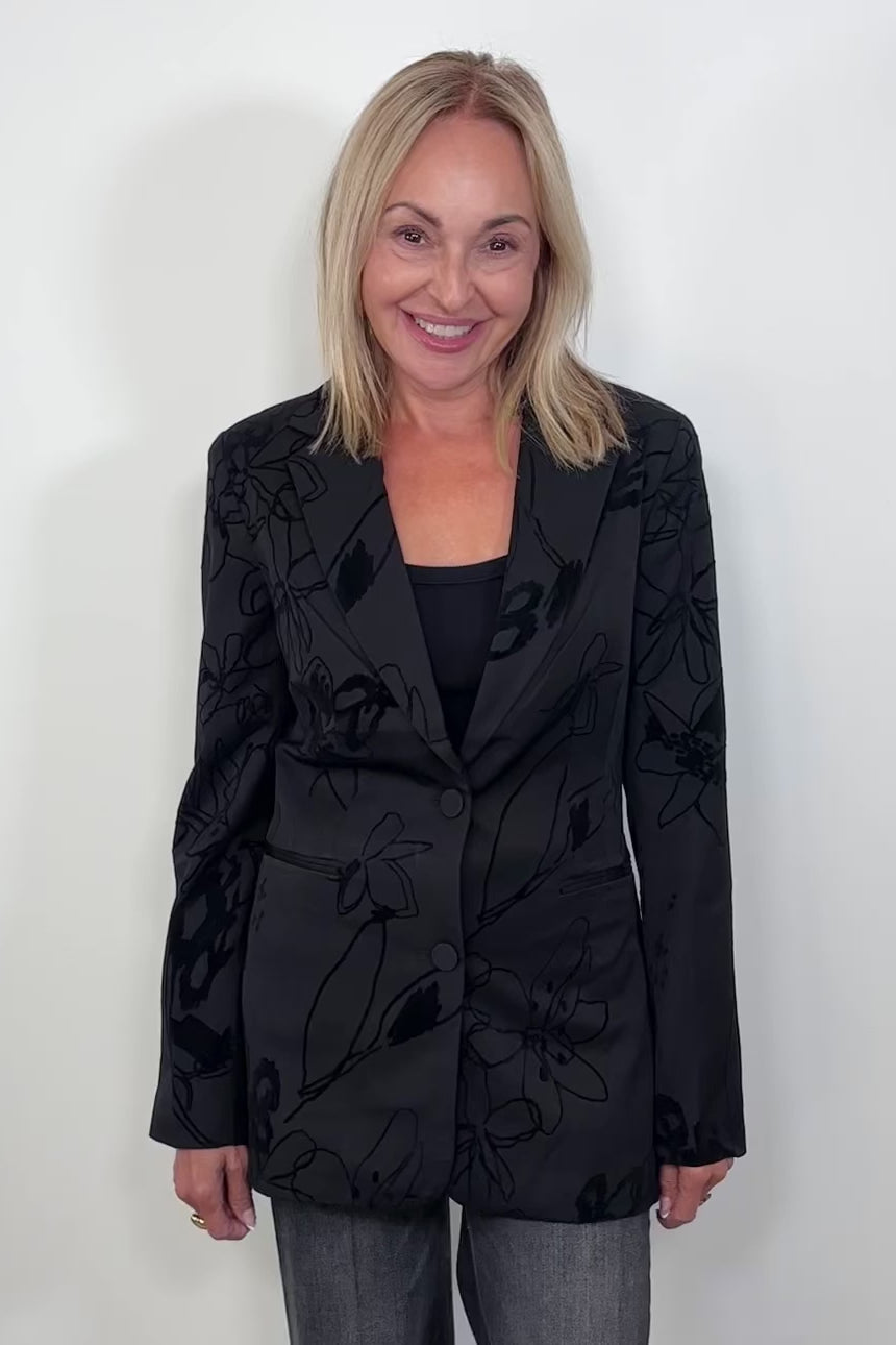 Video of woman wearing a black blazer with textures flowers detailing