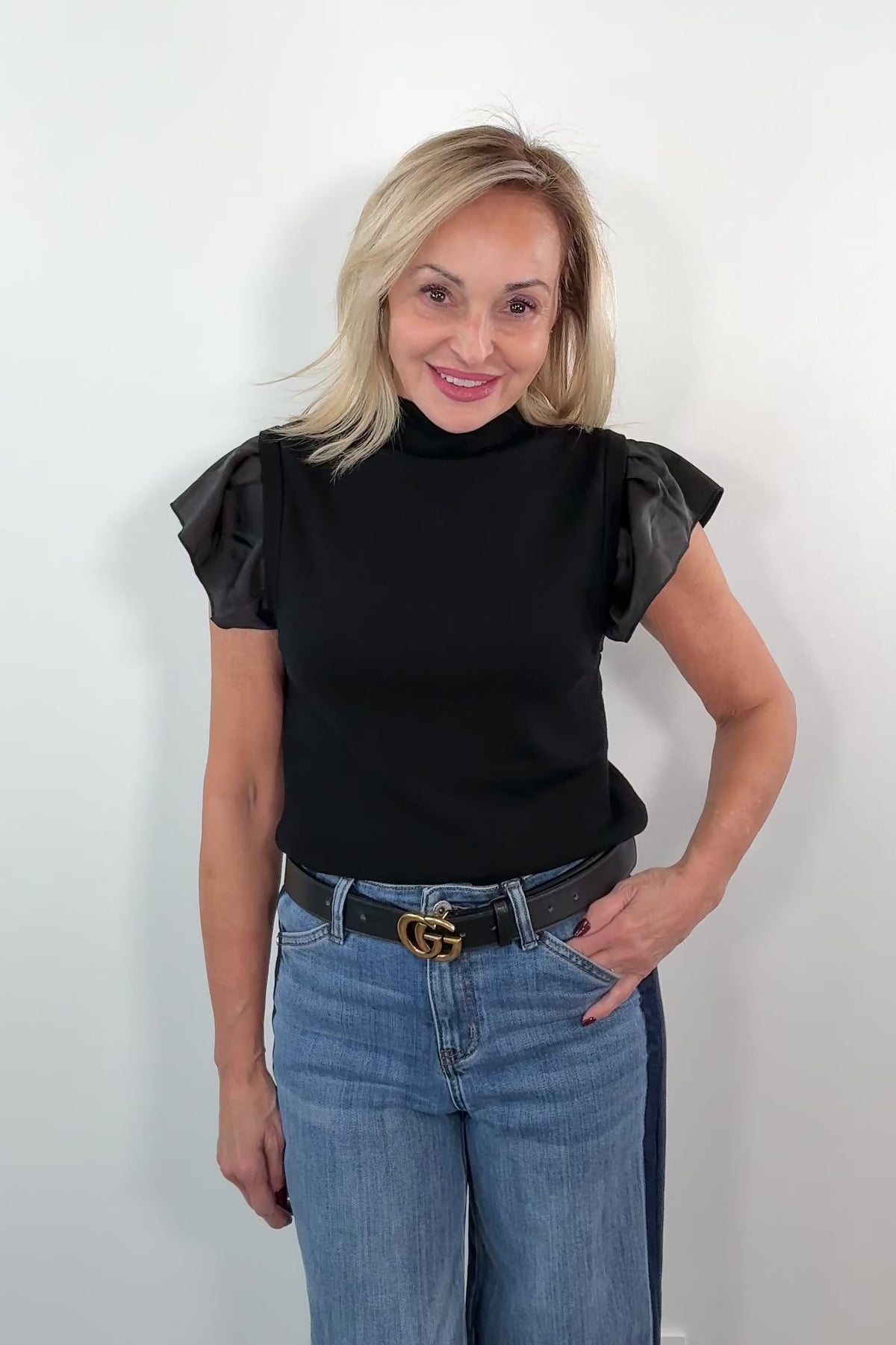 video of a woman wearing black sweater top with ruffle satin cap sleeves