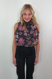video of a woman wearing a black sleeveless flower patterned ruffle top