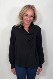 Video of a woman wearing a black blouse with ruffles and blue jeans 