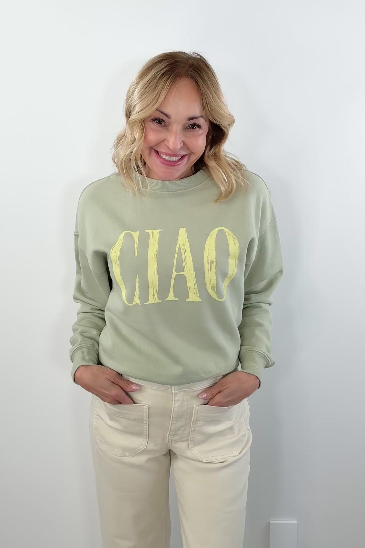 video of woman wearing matcha green pullover with "ciao" detial