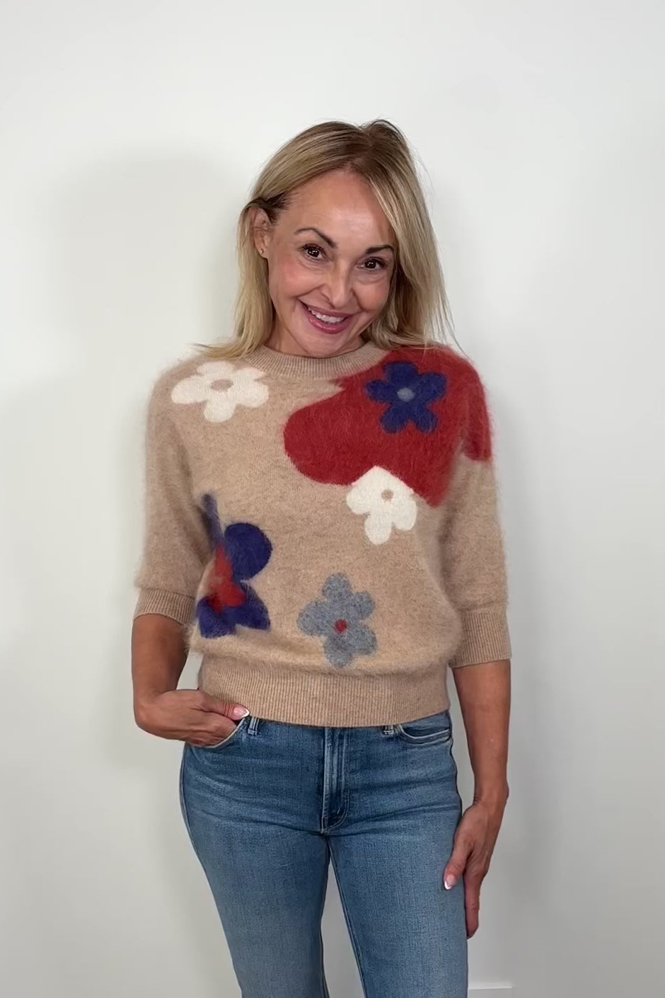 Video of a woman wearing a tan 100% brushed cashmere sweater with a flower pattern turning around to show the back