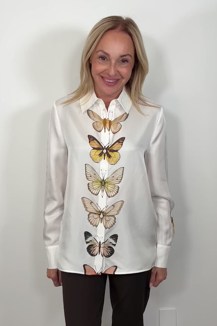 Video of woman wearing a butterfly patterned button up silk shirt 