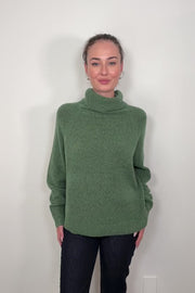 Video of woman wearing an oversized green knitted turtleneck 