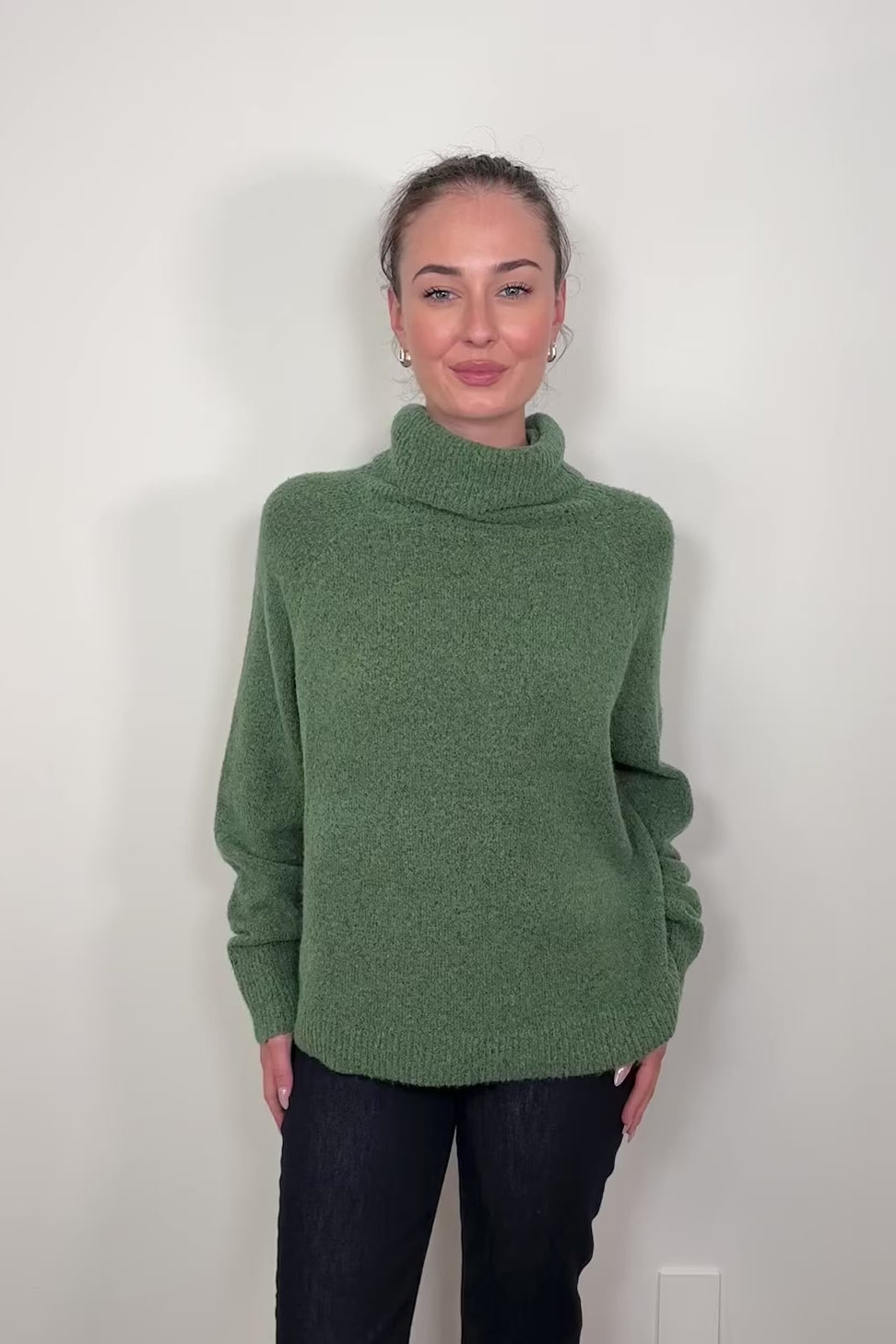Video of woman wearing an oversized green knitted turtleneck 