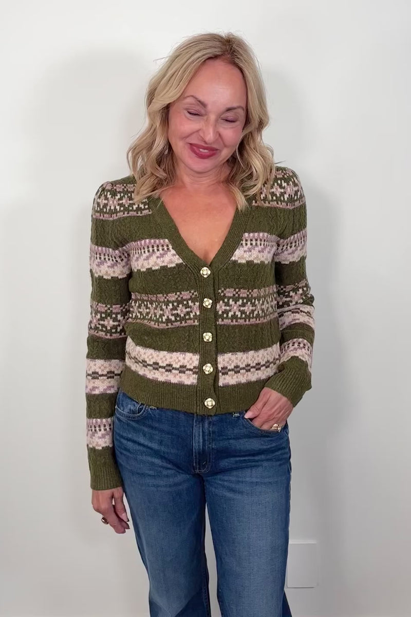 Video of a woman wearing a green patterned cardigan against a white background