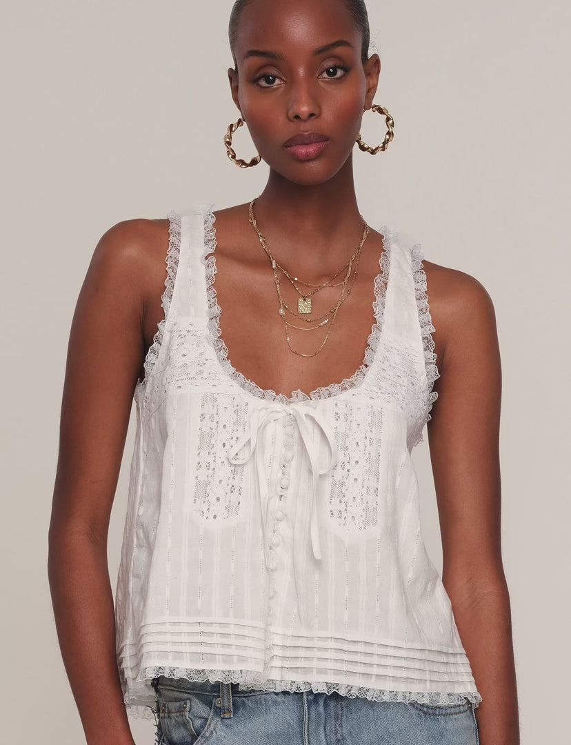 Woman wearing a white sleeveless top with lace detailing. 