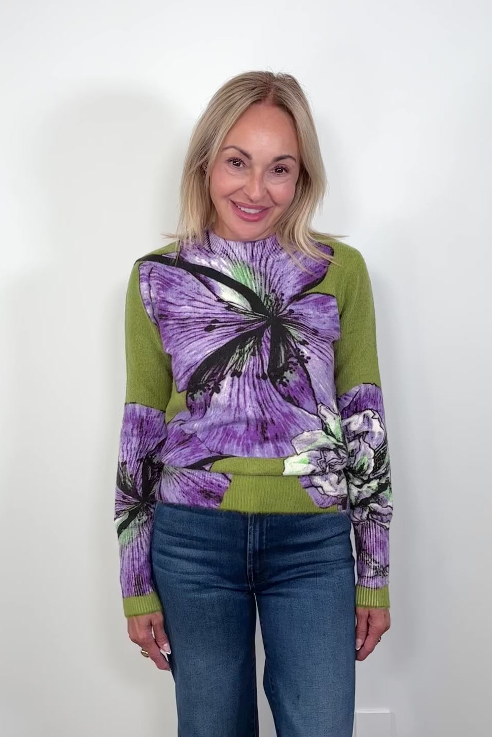 Video of woman wearing a green sweater with purple orchids all over