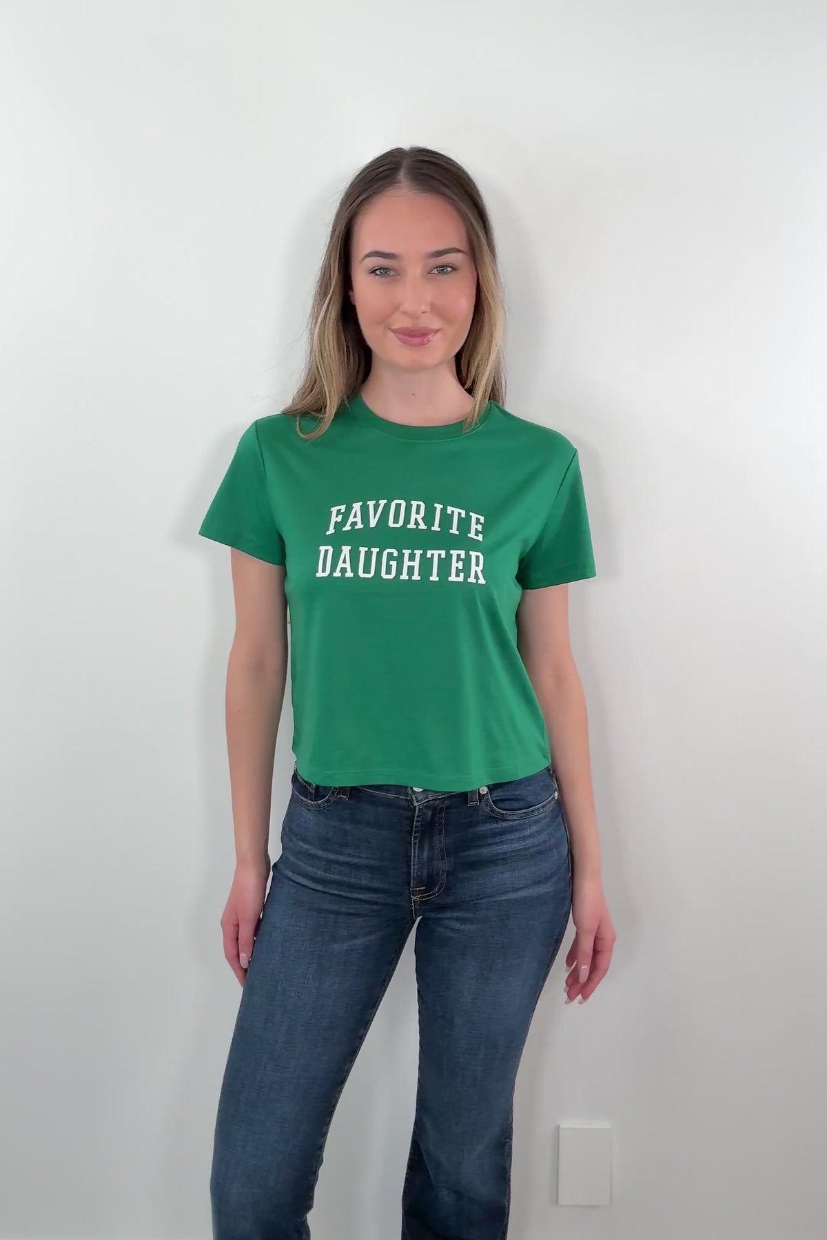 video of woman wearing a green t-shirt with 'FAVORITE DAUGHTER' text 