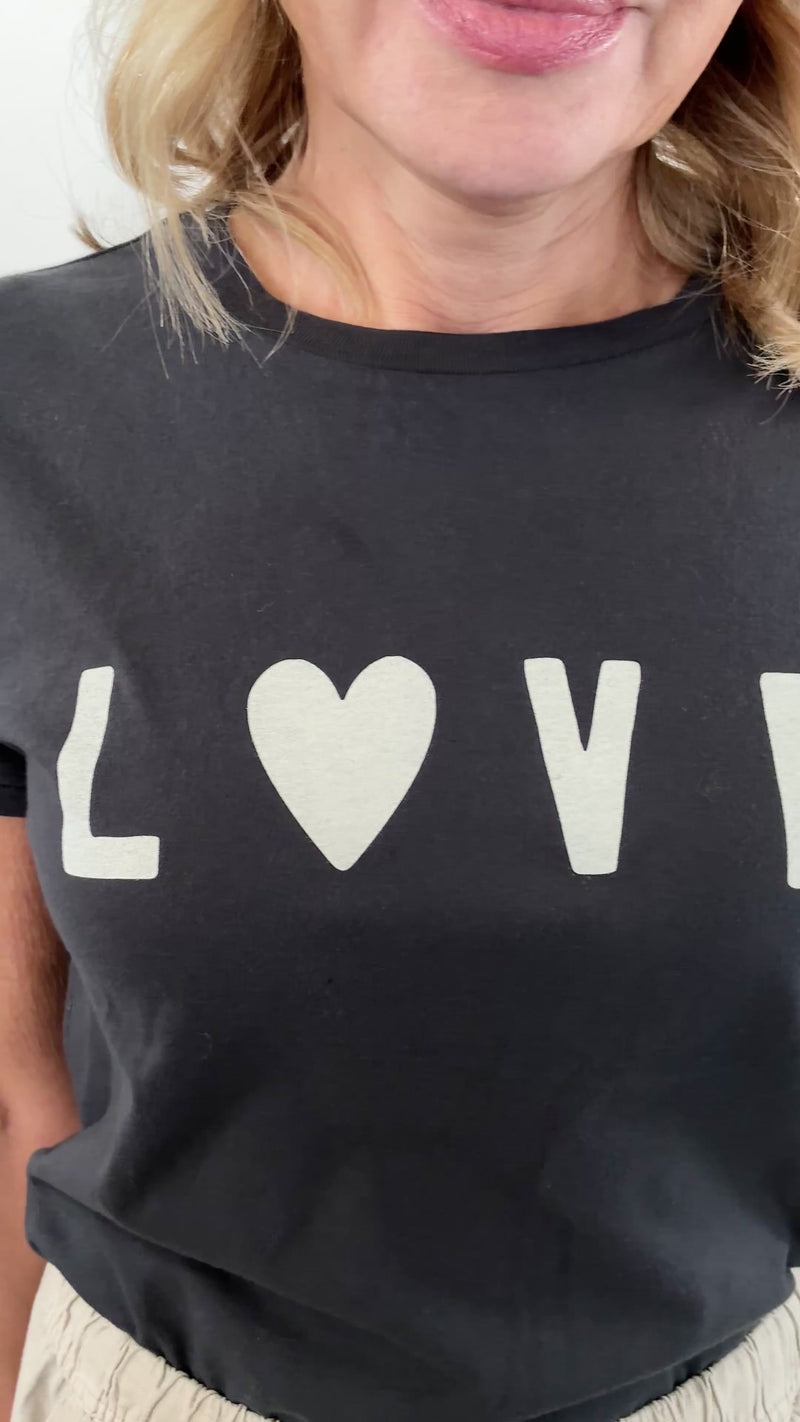 video of woman wearing a black tee shirt with the world "love" in the center of the chest with a heart instead of a O