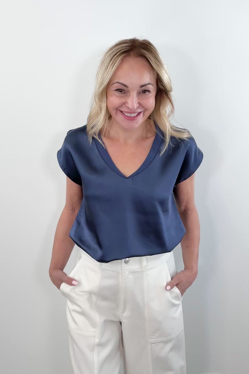 Video of a woman wearing a navy satin V-neck short-sleeve top