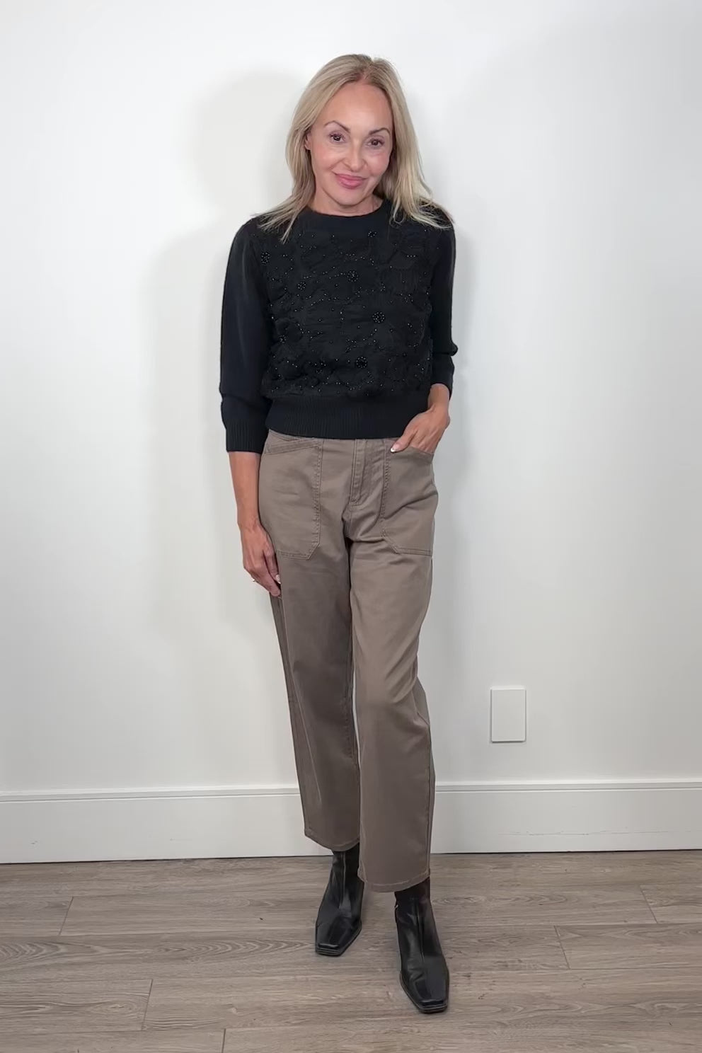 Video of woman wearing a pale brown pant with a black long sleeve top