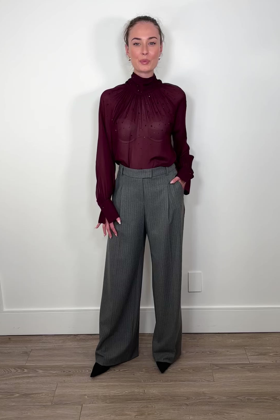 Video of woman wearing a gray pinstripe wide leg pant with a burgundy line down the leg
