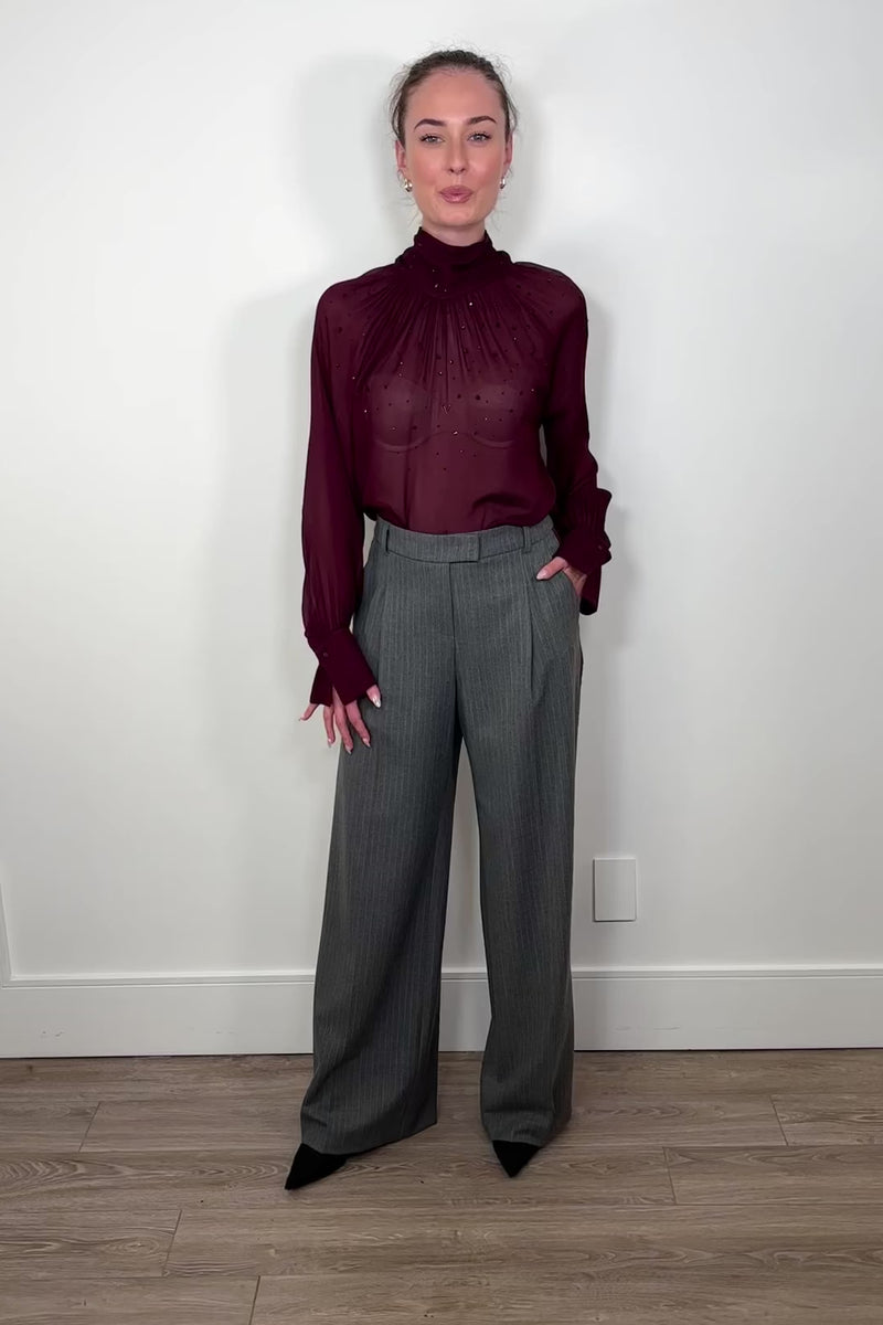 Video of woman wearing a gray pinstripe wide leg pant with a burgundy line down the leg