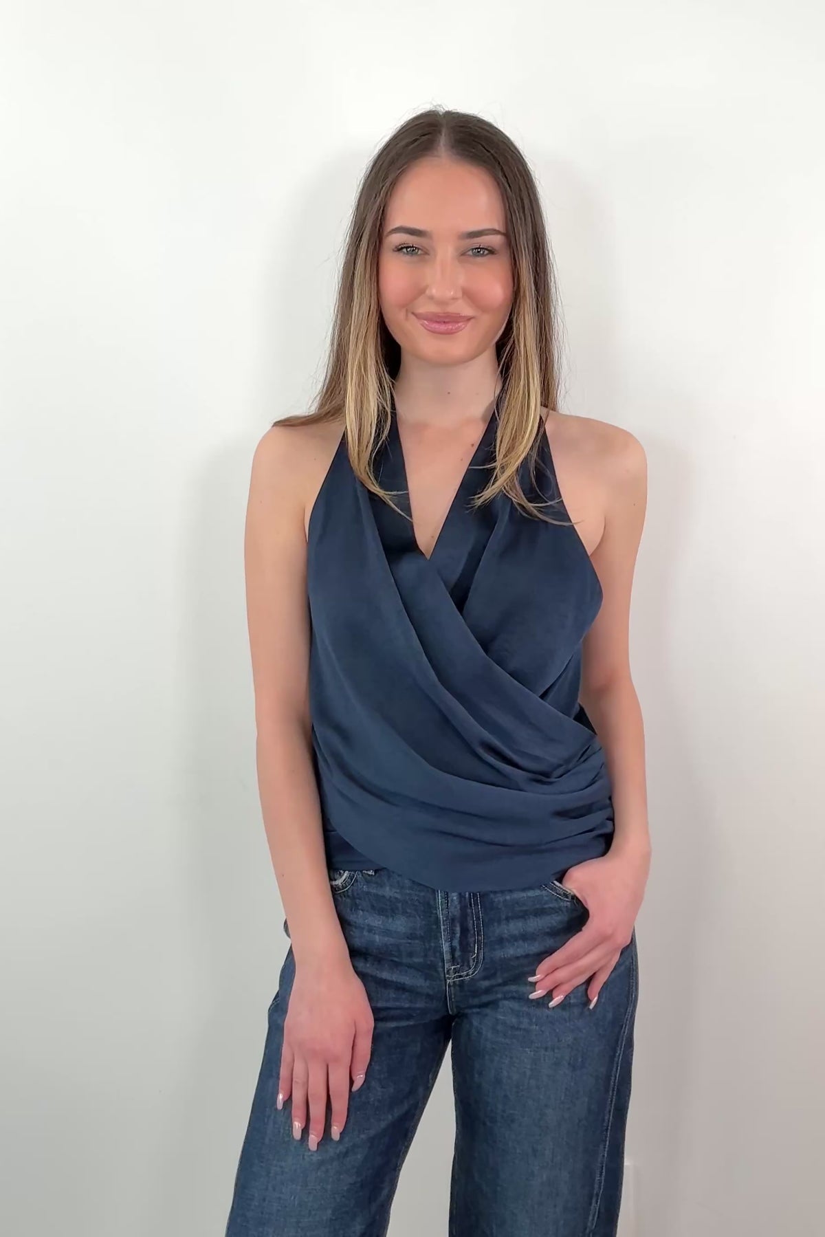 Video of Woman wearing a satin draped halter top in navy blue