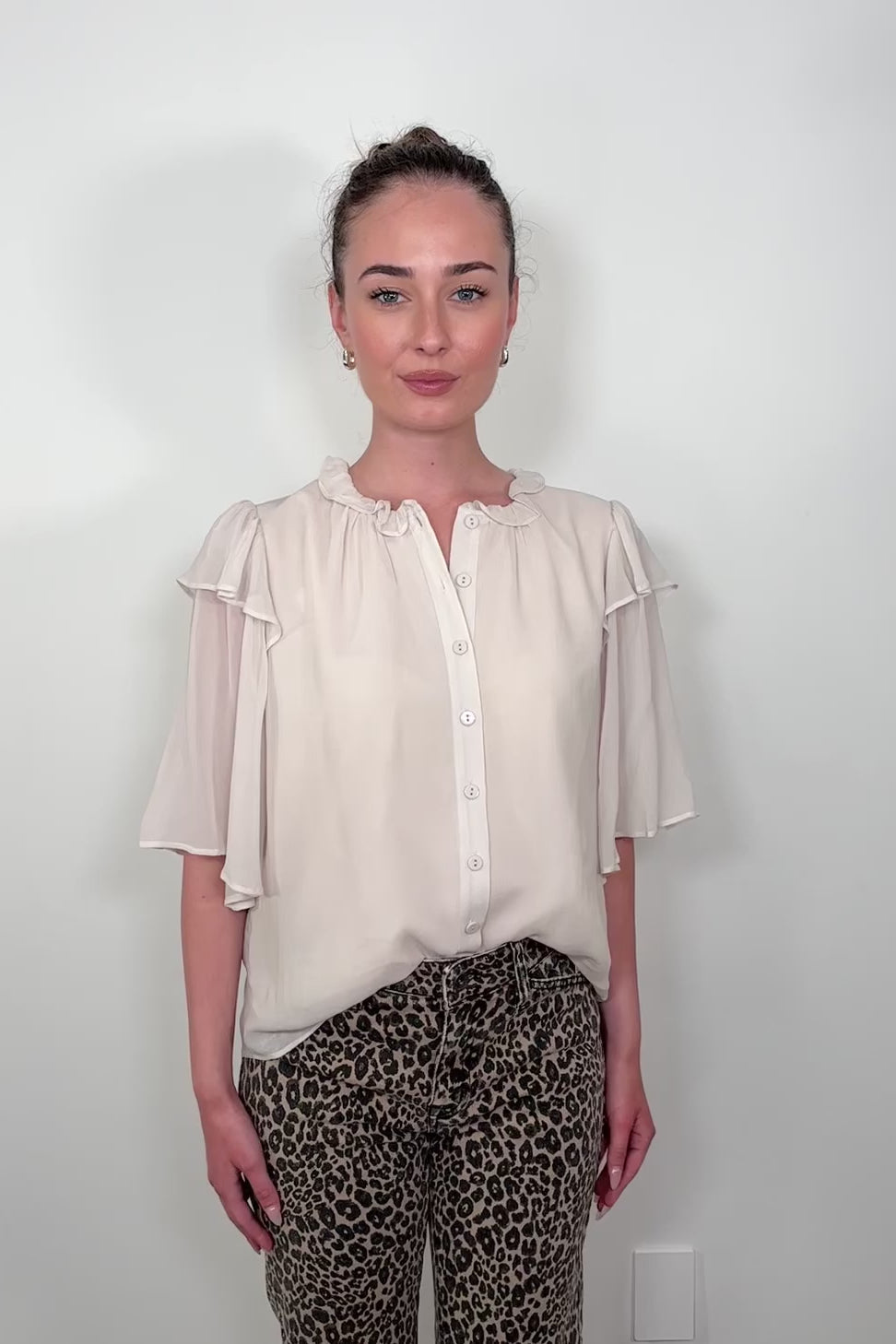 Video of woman wearing an oat coloured light blouse