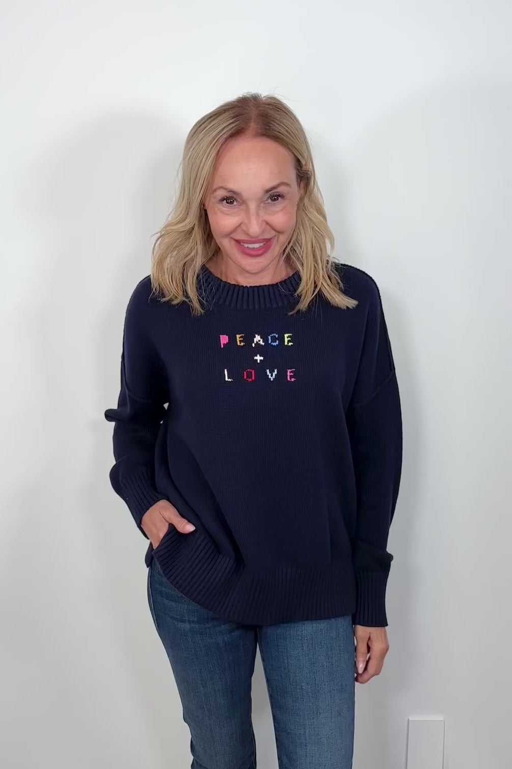 Video Woman wearing a navy blue sweater with “Peace & Love” embroided