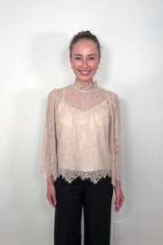 Video of a woman wearing a lined long sleeve beige lace blouse 