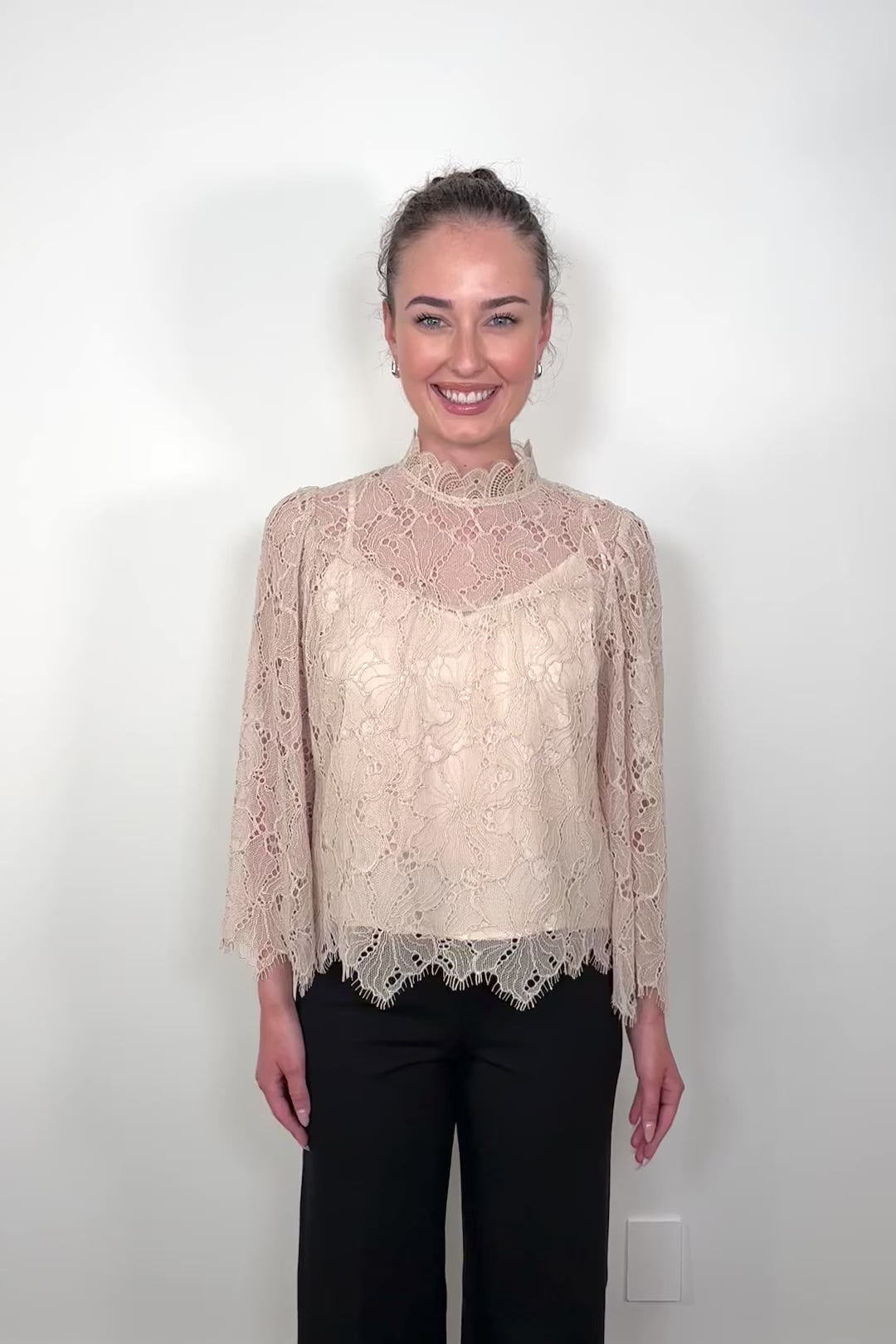 Video of a woman wearing a lined long sleeve beige lace blouse 
