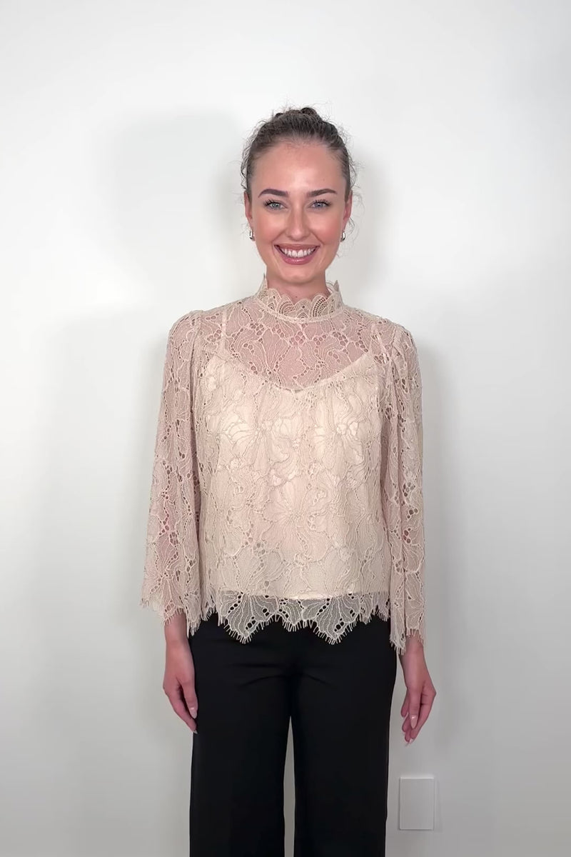 Video of a woman wearing a lined long sleeve beige lace blouse 