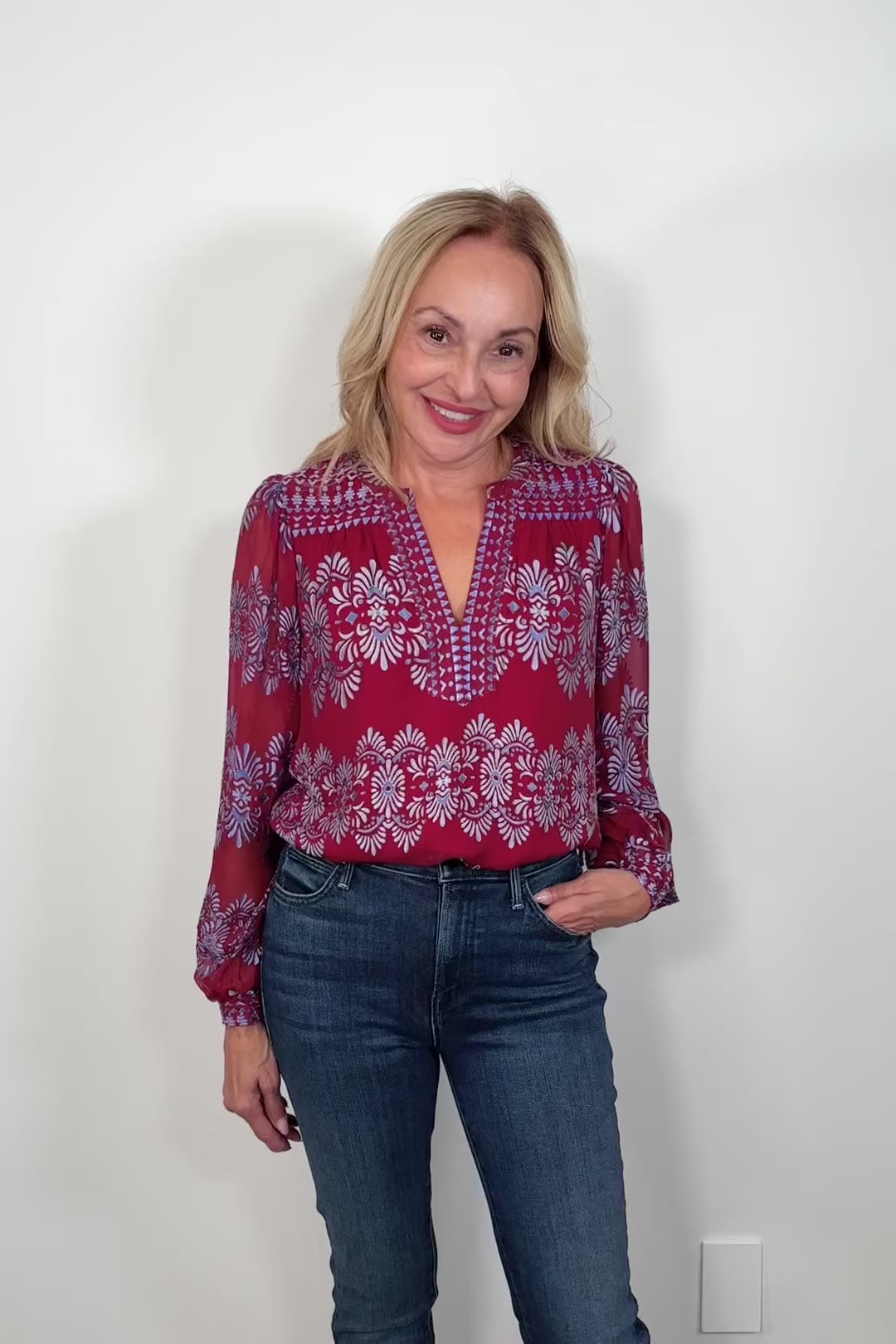 Video of woman wearing a silk mix red long sleeve burnout blouse tucked in